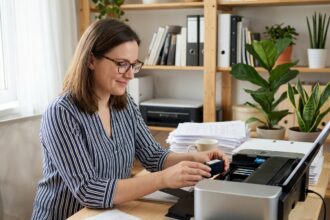 Femme dans un bureau à domicile remplaçant une cartouche d'encre