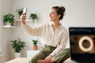 Influenceuse enregistrant une vidéo sur smartphone dans un studio home office minimaliste pour une campagne de notoriété de marque