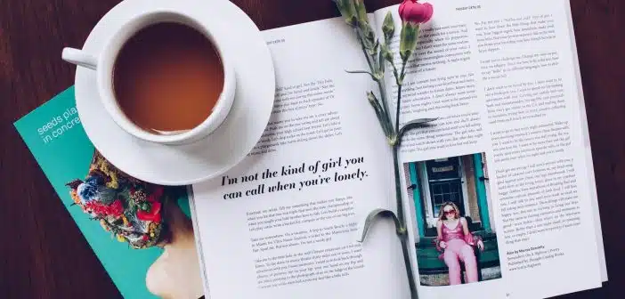 opened book with pink flower on top near filled ceramic mug